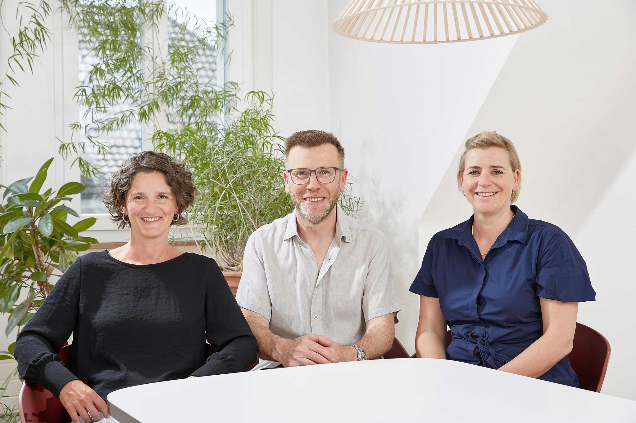 Die Coaches von Musterintegration sitz in ihrem Studio für Beratung und lächeln in die Kamera.